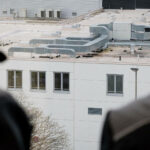 2 Mitarbeiter der SSN Gebäudetechnik schauen auf die Lüftungsanlage auf dem Dach des Nachbargebäudes